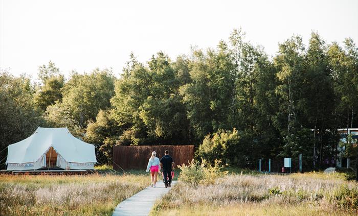 Canvas tent and board walk over the marsh by the entrance to the camping meadow